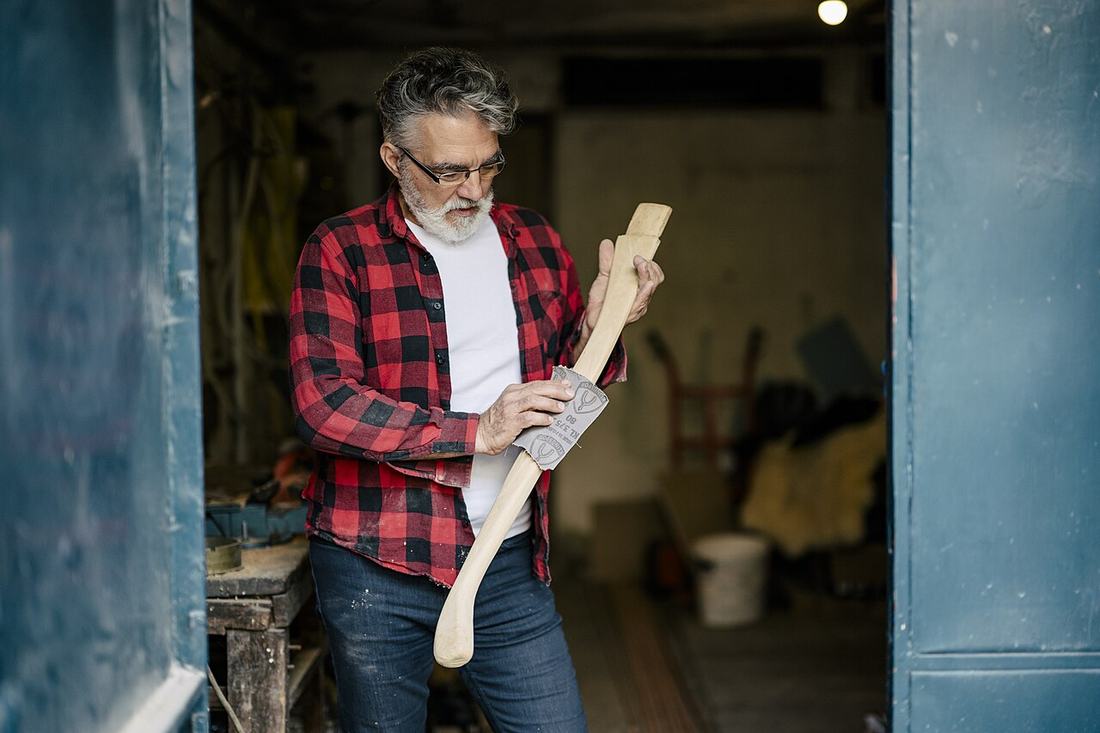 Craftsman shaping wooden piece in workshop during daytime